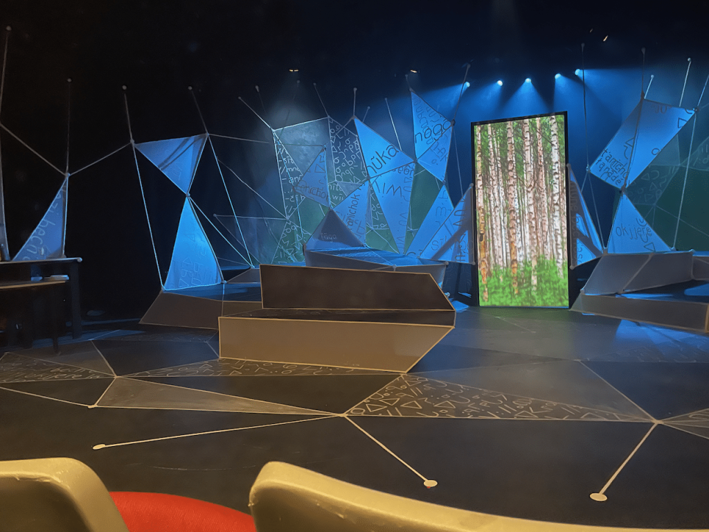 Photograph of a stage with blue light highlighting triangular shapes.