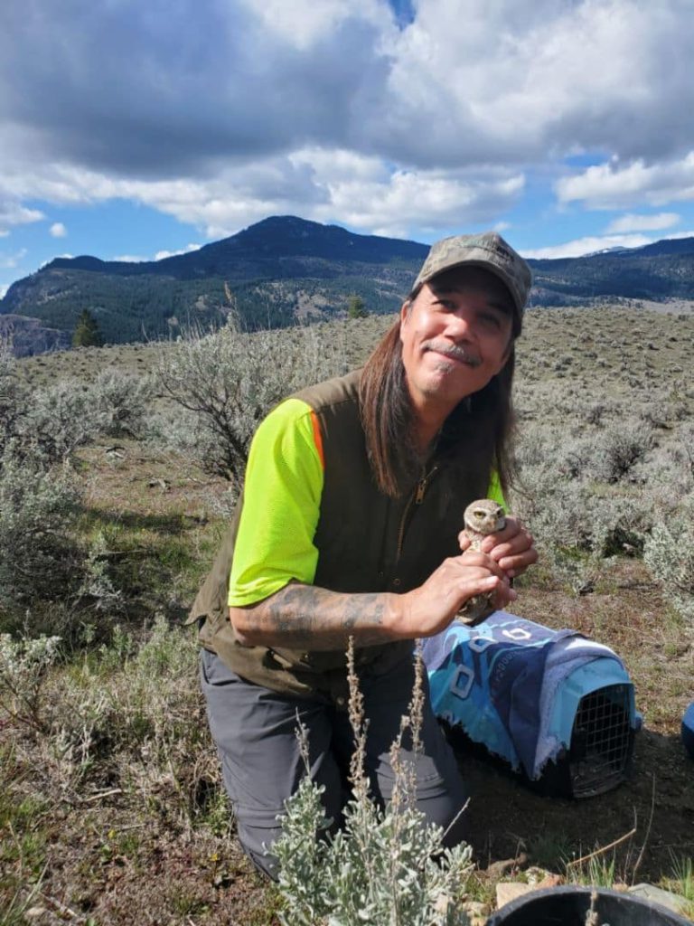 PIB Indigenous guardian Dean Schreiber holds a burrowing owl in his hands.