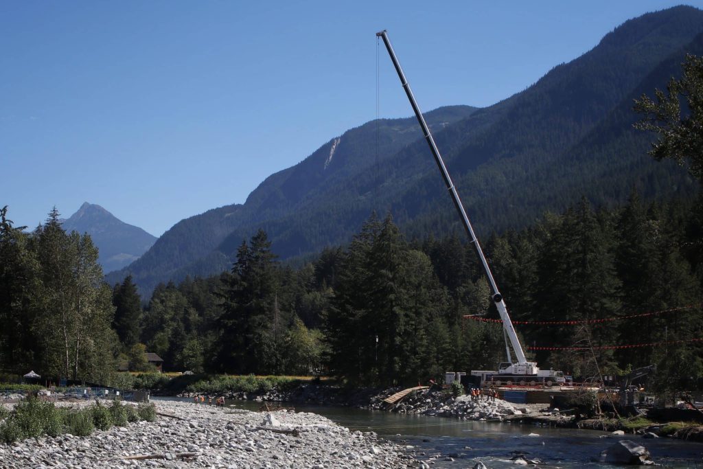 A crane is seen operating over the river from the TMX project site on the river bank.