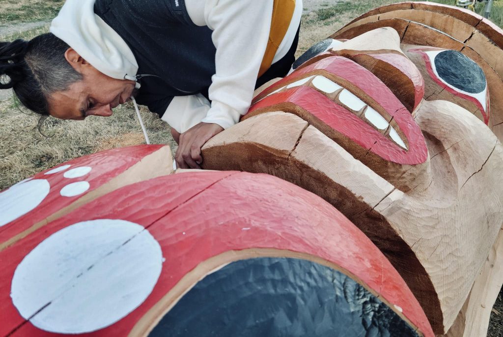 Carver Ernest Puglas carving a welcome pole our of a huge log.
