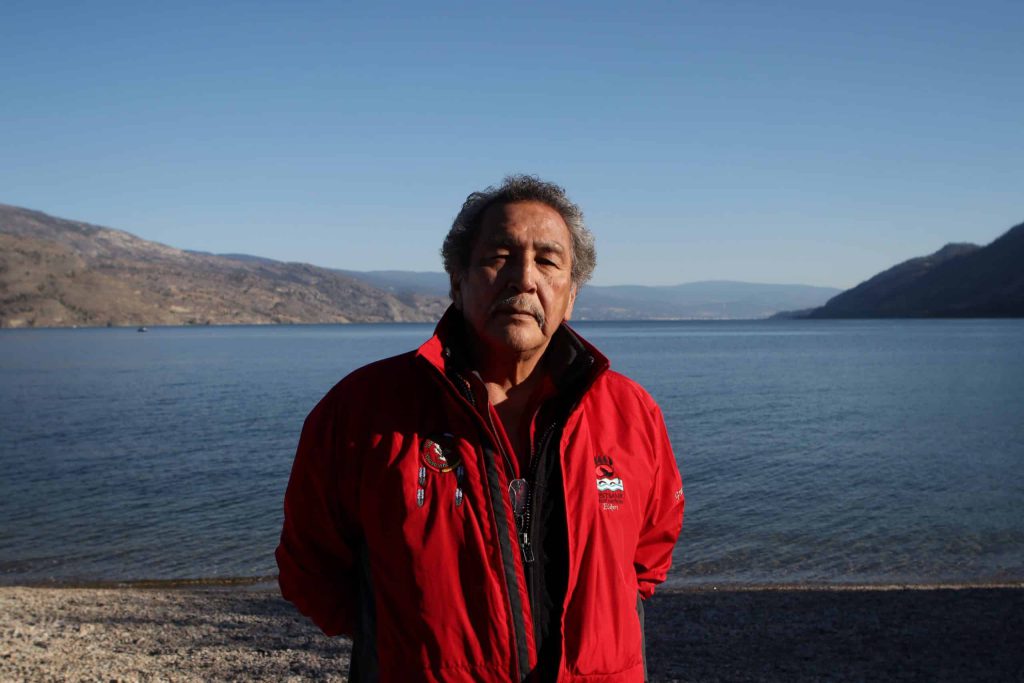 K̓ninm̓tm̓ taʔ n̓q̓ʷic̓tn̓s Wilfred “Grouse” Barnes, a syilx Elder and knowledge keeper from Westbank First Nation, stands at the shore of Okanagan Lake in syilx homelands on Sept. 25. Photo by Aaron Hemens