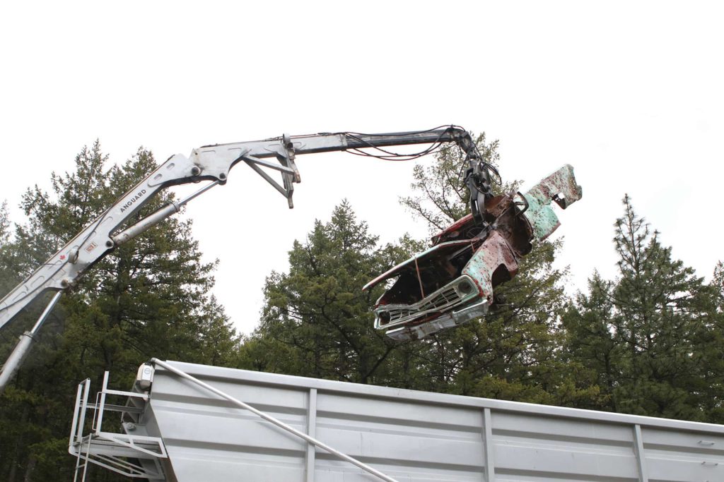 An abandoned car riddled with bullet holes is lifted in a dump truck during a cleanup of “Peachland’s” watershed in syilx homelands on April 30. Photo by Aaron Hemens