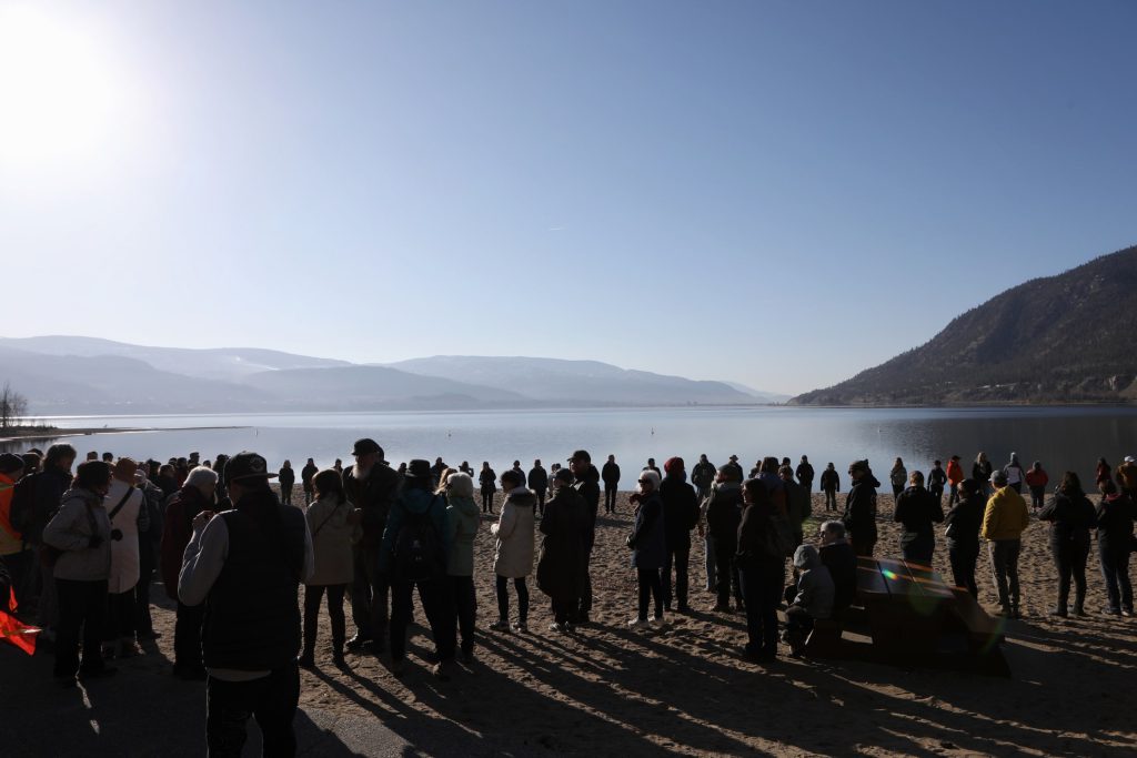 People maneuver themselves into a circle formation at the shore of cnxəlkip (Sun-Oka Beach Park) by kɬúsx̌nítkʷ (Okanagan Lake) on March 22. Photo by Aaron Hemens