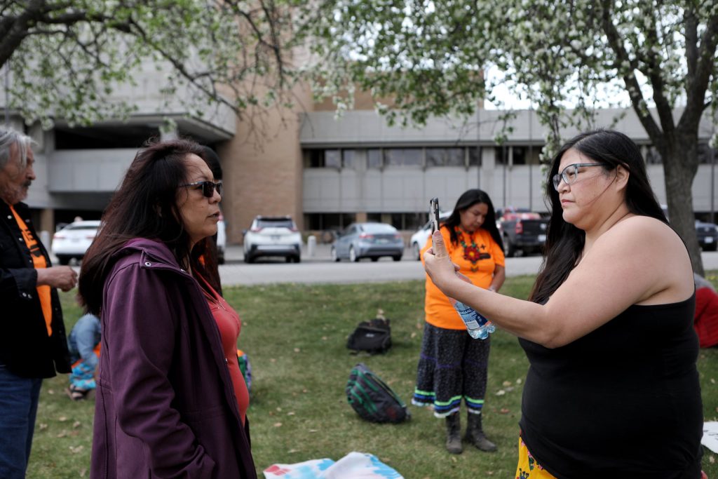 Secwépemc Matriarch April Thomas, left, and Red Deer Billie Pierre of Nlaka’pamux Nation conduct a livestream outside of the Kamloops Law Courts building in Tk’emlúps (Kamloops) on May 1, ahead of the first day of their sentencing hearing. The two were arrested and charged with criminal contempt for breaching a Trans Mountain Pipeline injunction-protected construction area in Secwepemcúl’ecw in October 2020. (Photo by Aaron Hemens)