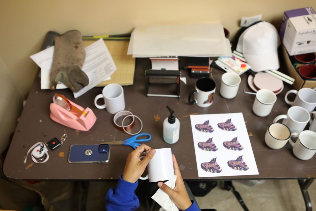 Paige Janvier prepares to apply Ojibwe artist Sarah Jones’s Pride design to various mugs at the Ki-Low-Na Friendship Society in syilx homelands on May 22. Photo by Aaron Hemens
