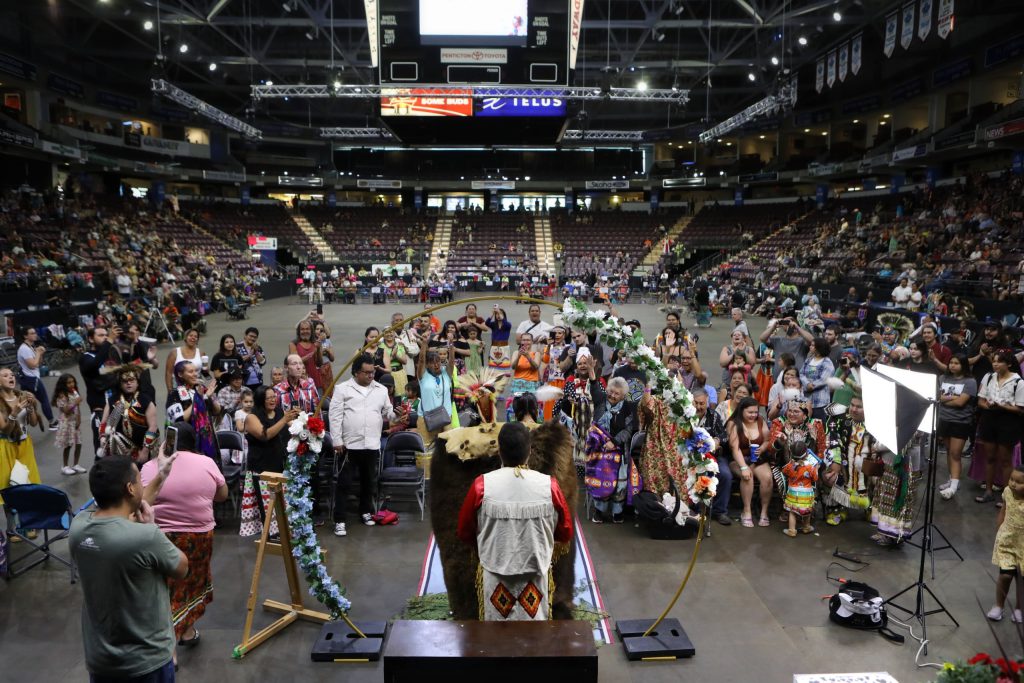 The community watches as Tyrone Kruger and Nicole (Schellenberg) Kruger are joined in marriage during the Four Seasons Cultural Society’s 2023 Between the Lakes Powwow at the South Okanagan Events Centre in snpink'tn (Penticton) in syilx homelands on June 24. Photo by Aaron Hemens