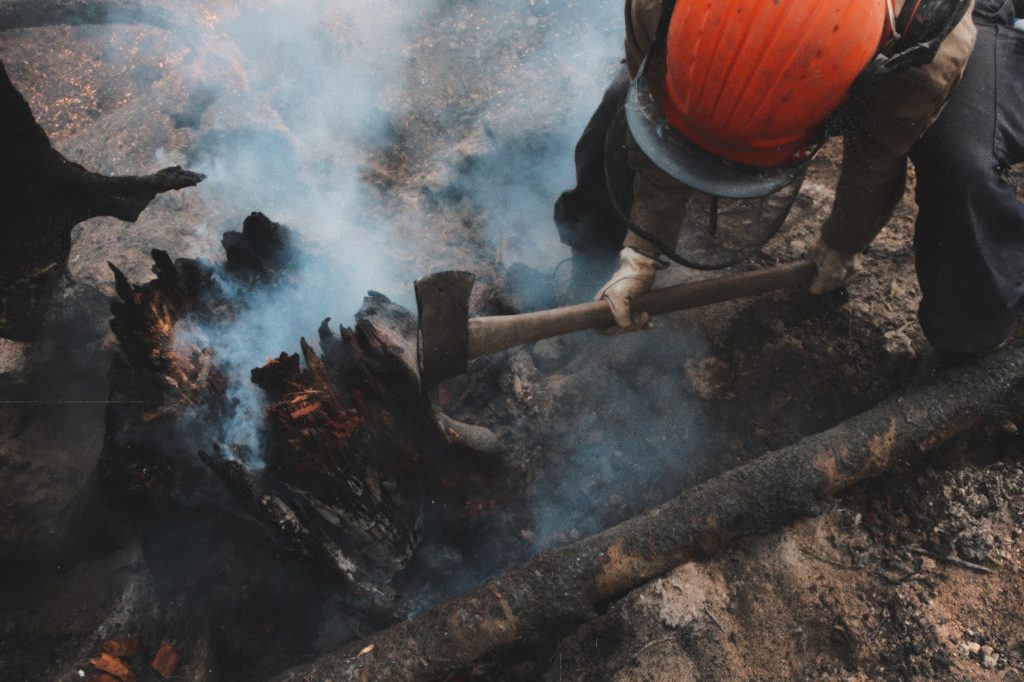 A wildfire fighter attempts to extinguish a burning stump during the 2023 wildfire season. Photo by Mike Graeme