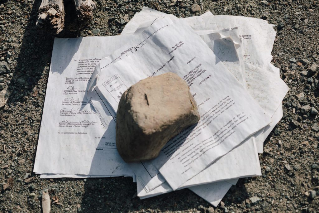 Stacked-up injunction papers were served to the Savage Patch blockade camp by Teal Jones in Pacheedaht territory near “Port Renfrew” on “Vancouver Island” on Aug. 6, 2023. Photo by Amber Bracken 