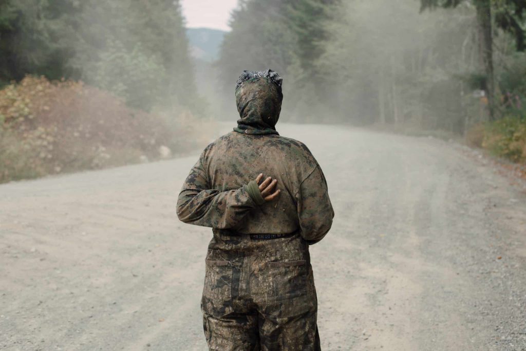 An Indigenous land defender looks up the road after a pick-up driver accelerated towards them at Savage Patch camp in Pacheedaht territory near “Port Renfrew” on “Vancouver Island”  on Aug. 8, 2023. Photo by Amber Bracken