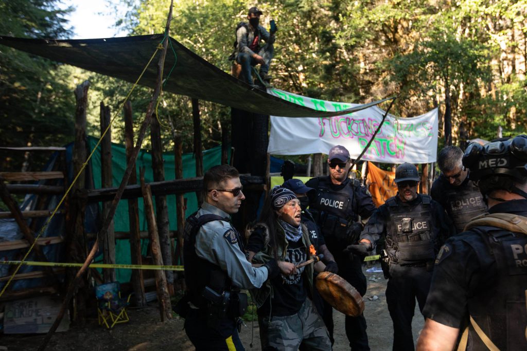 RCMP CIRG officers arrest Uncle Ricco at Savage Patch, a camp blockading old growth logging, in Pacheedaht territory near “Port Renfrew” on “Vancouver Island” on Aug. 15, 2023. Three people were arrested and released without charges. Photo by Amber Bracken 