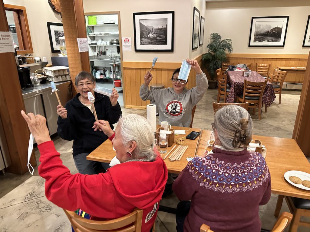 Elders and students laugh while showing the drumsticks they were forced to make with masks because they forgot to pack the traditional supplies. Photo by Eden Fineday