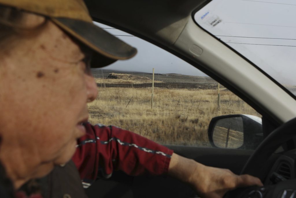 Dixon Terbasket, a syilx Okanagan wildlife technician with the Okanagan Nation Alliance from the Lower Similkameen Indian Band, drives by a fenced-off cherry orchard expansion site near Kelowna, British Columbia, on Dec. 7, 2023. Terbasket and other conservation experts are concerned that the cherry orchard's expansion is impacting the mobility of animals that use a nearby wildlife corridor in an area under threat from urban sprawl and other development. Aaron Hemens/IndigiNews via AP
