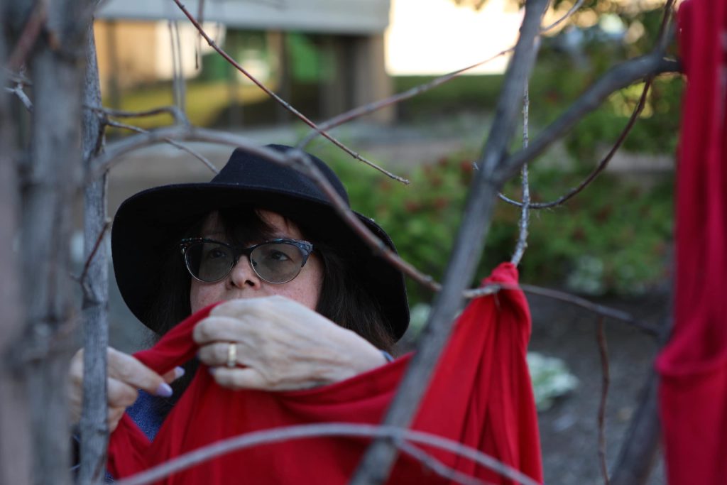 Janet Enoch hangs red dresses up on a tree to honour Missing and Murdered Indigenous Women, Girls and Two-Spirit people (MMIWG2S) during a rally to stop violence against women outside of Kamloops Courts in Secwepemcúl'ecw on June 20. Photo by Aaron Hemens