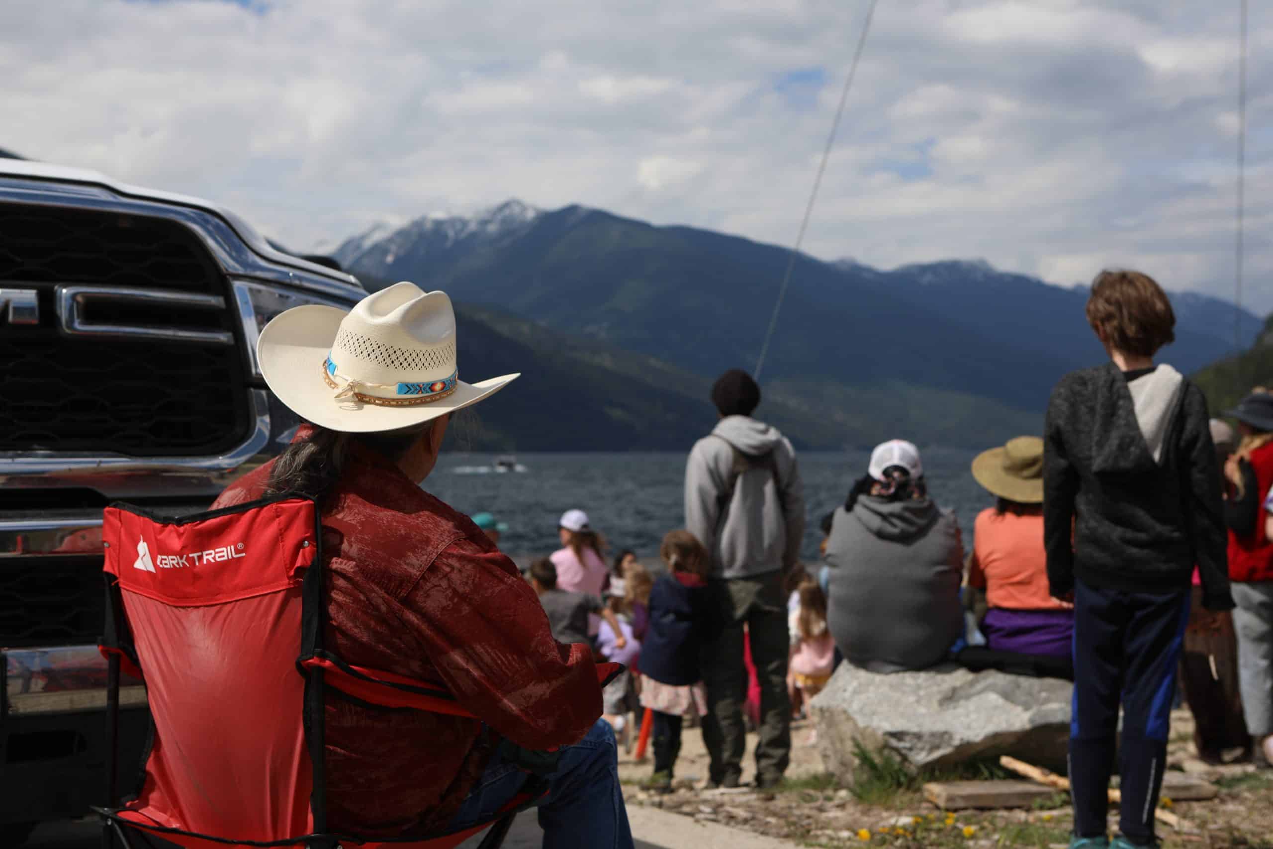 cewel’na Leon Louis, a syilx knowledge keeper, watches on as Youth release salmon fry into Slocan Lake in syilx Okanagan territory during a ceremonial release hosted by the Okanagan Nation Alliance on May 13, 2024. Photo by Aaron Hemens