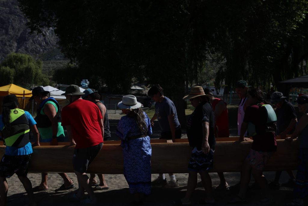 Community members carry a canoe to nk’mip (Osoyoos Lake) in sw̓iw̓s (Osoyoos) prior to the launch of the 2024 Sukʷnaqin canoe journey. Photo by Aaron Hemens