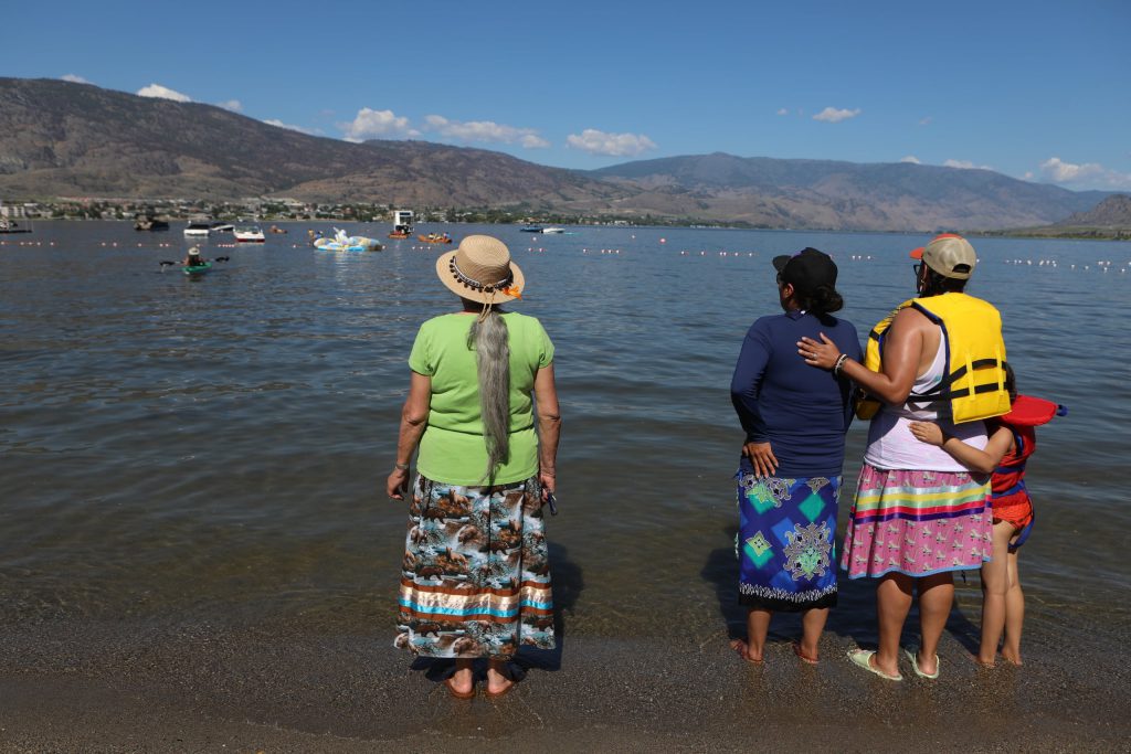 Community members watch as canoes set sail on the 2024 Sukʷnaqin canoe journey. Photo by Aaron Hemens