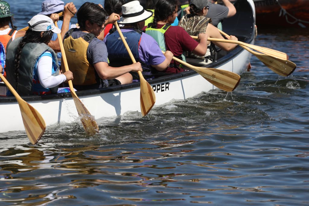 syilx Okanagan community members paddle on nk’mip (Osoyoos Lake) in sw̓iw̓s (Osoyoos) for the 2024 Sukʷnaqin canoe journey. Photo by Aaron Hemens