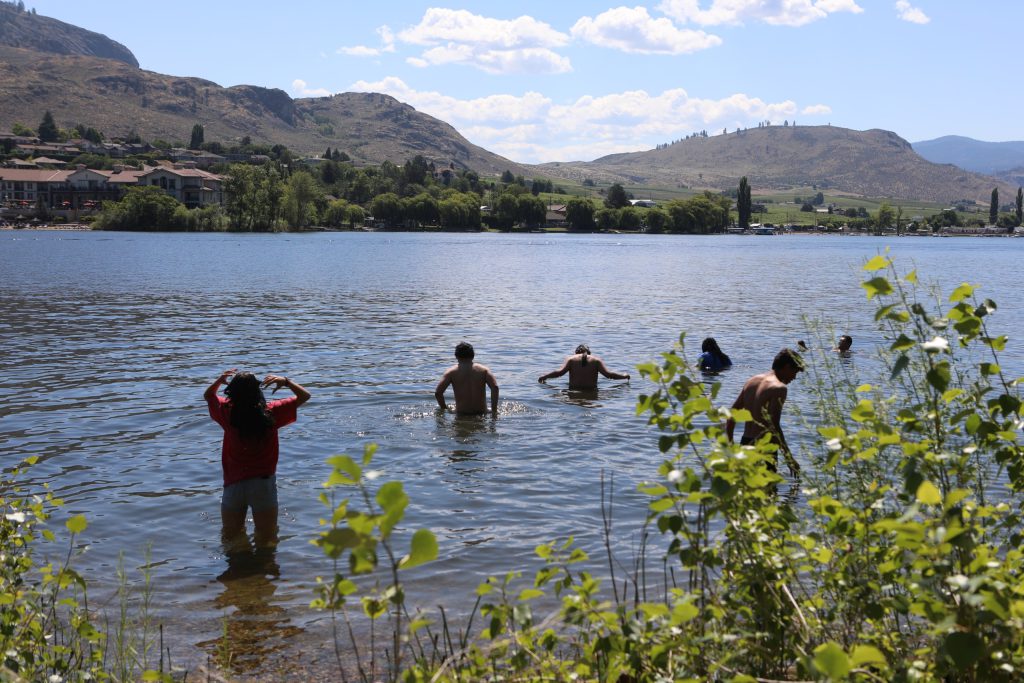 Paddlers go for a swim at sw̓iw̓s (Haynes Point) Provincial Park during the 2024 Sukʷnaqin canoe journey. Photo by Aaron Hemens