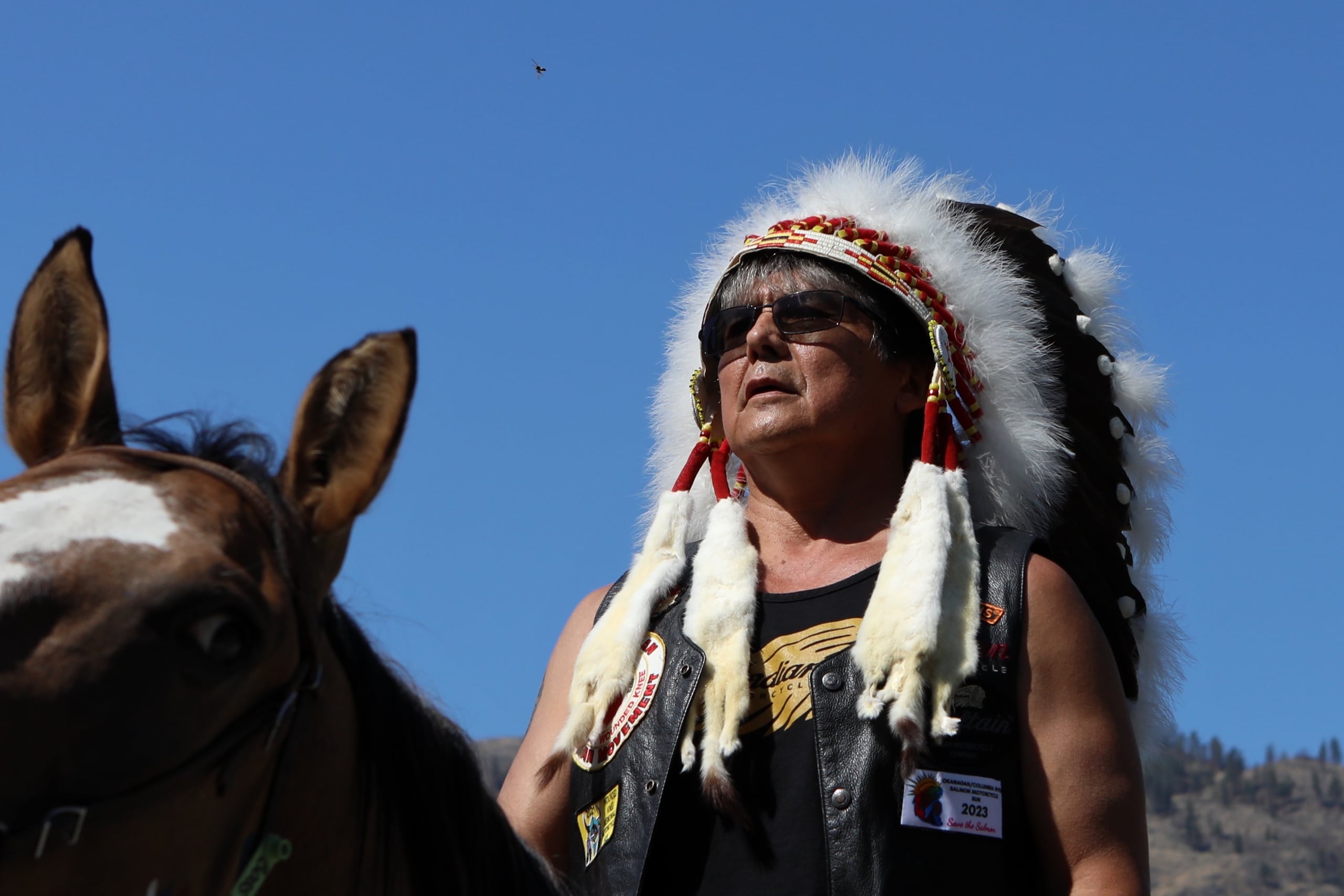 ki law na Clarence Louie, y̓ilmixʷm (Chief) of Osoyoos Indian Band (OIB), prepares to cross into the “U.S.” from “Canada” via horseback at the “Osoyoos-Oroville” border in syilx Okanagan homelands on July 20. Photo by Aaron Hemens
