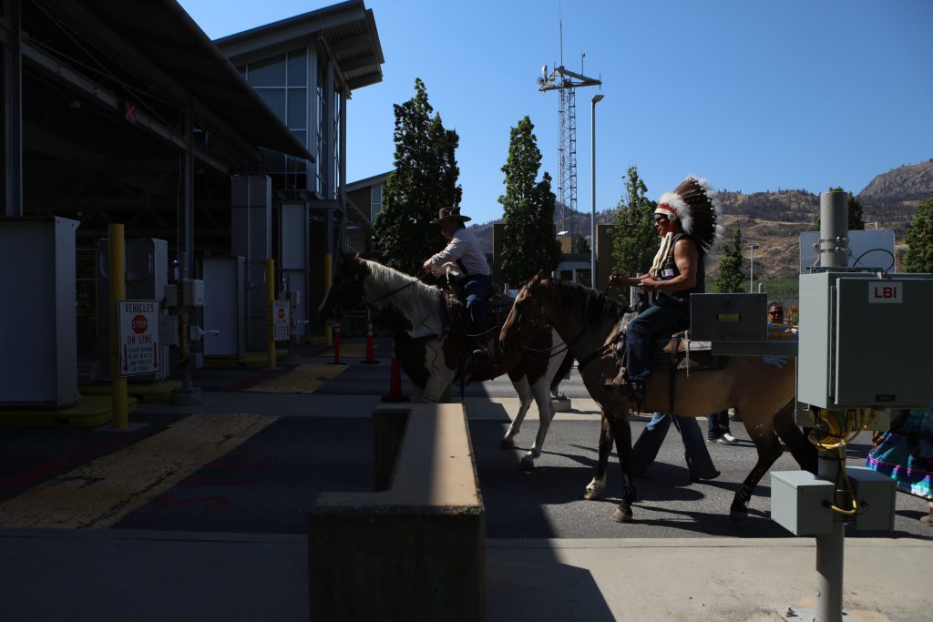The group of riders cross into the “U.S.” from “Canada” at the “Osoyoos-Oroville” border in syilx Okanagan homelands on July 20. Photo by Aaron Hemens