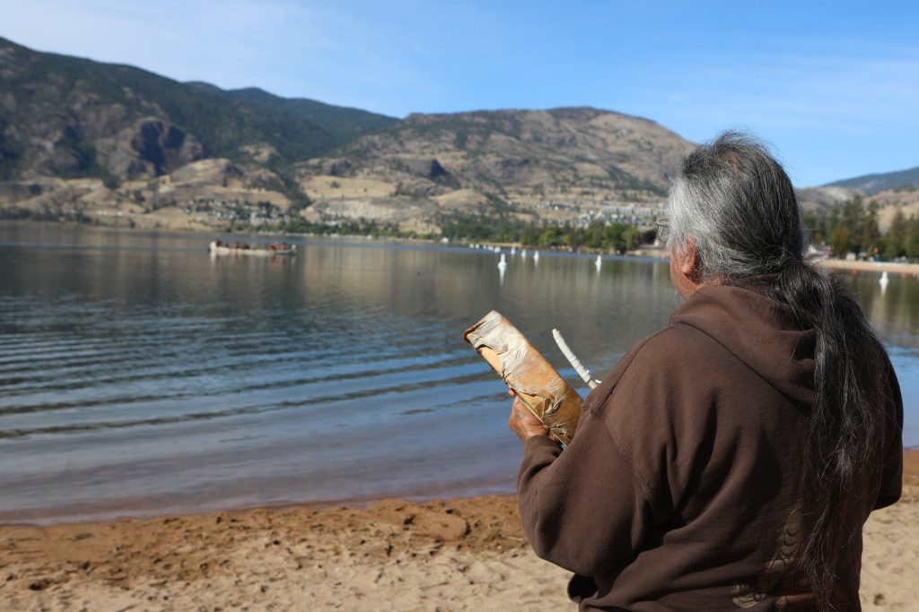 Herman Edward, of the Lower Similkameen Indian Band, sings a drum song as canoes make their way from Skaha Lake to sx̌ʷəx̌ʷnitkʷ (Okanagan Falls) on Sept. 21, during the syilx Nation’s 2024 salmon feast and celebration weekend. Photo by Aaron Hemens