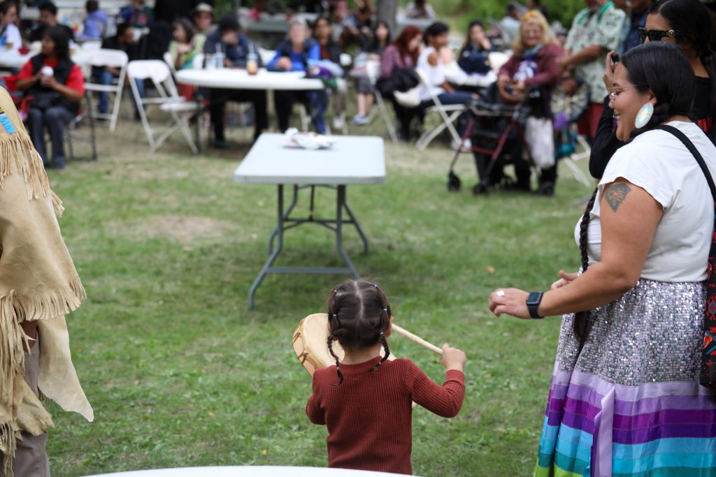 A young drummer plays at the syilx Nation’s 2024 salmon feast and celebration at sx̌ʷəx̌ʷnitkʷ (Okanagan Falls) on Sept. 22. Photo by Aaron Hemens