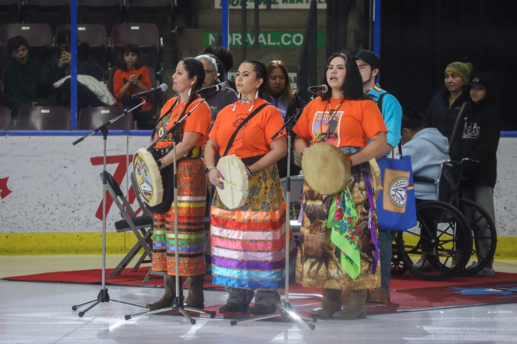 Wynona Paul, centre, sings the Okanagan Song with family and community during the opening ceremony of the Penticton Vees’ home game in syilx Okanagan territory on Jan. 31. Photo by Aaron Hemens