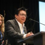 Chief simo Robert Louie of Westbank First Nation, co-chair of the Okanagan-Similkameen Collaborative Leadership Table, speaks at the Okanagan Nation Alliance's 2026 siwɬkʷ (Water) and Climate Forum on March 23 in Kelowna, B.C. Behind him is fellow co-chair Tricia Brett, councillor for the District of Lake Country. Photo by Aaron Hemens