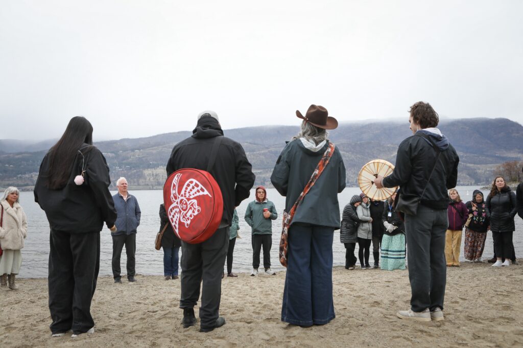 Members of the syilx Okanagan Nation sing drum songs following a water ceremony at kɬúsx̌nítkʷ (Okanagan Lake) on March 24, 2026, during the Okanagan Nation Alliance's siwɬkʷ (Water) and Climate Forum in Kelowna, B.C. Photo by Aaron Hemens