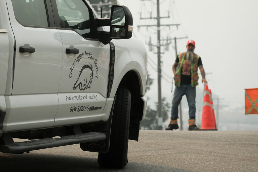 Emergency personnel prepare to let a work vehicle with the Okanagan Indian Band into the north end of Westside Road, one of the entrances to the Okanagan Indian Band, on Aug. 5, 2026. With the Bradley Creek wildfire still active, evacuation orders remain in place for hundreds of people in the area. Photo by Aaron Hemens
