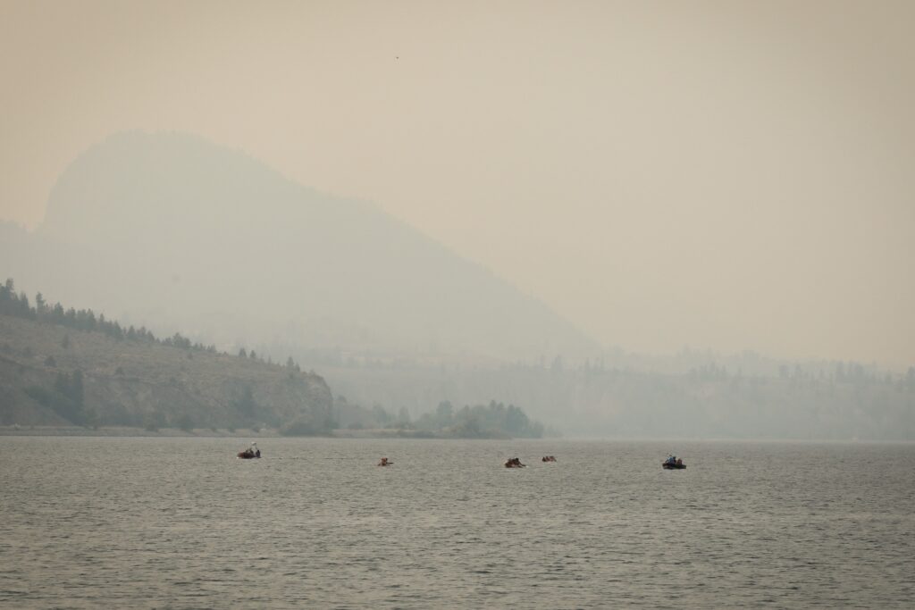 Accompanied by two safety boats, three dugout canoes with the syilx Nation’s 2026 Unity Trek Commemorative Paddle near the shores of Penticton on July 30. The canoes were carved by Herman Edward, who participated in the original journey in 2001. Photo by Aaron Hemens