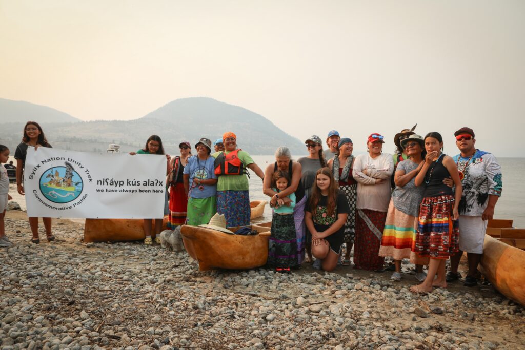 Paddlers with the syilx Nation’s 2026 Unity Trek Commemorative Paddle pose for a picture together on July 30 after arriving in Penticton, following five-days of paddling on Okanagan Lake. The canoes were carved by Herman Edward, who participated in the original journey in 2001. Photo by Aaron Hemens