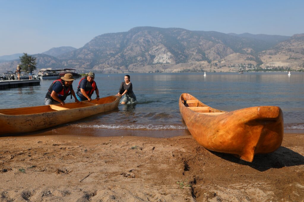 Community members prepare dugout canoes for departure at Skaha Lake on July 31, before departing for Okanagan Falls later that morning. The canoes were carved by Herman Edward, who participated in the original journey in 2001. Photo by Aaron Hemens