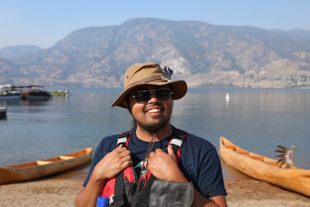Tristan Marshall stands near three dugout canoes at Skaha Lake on July 31, before departing for Okanagan Falls later that morning. The canoes were carved by Herman Edward, who participated in the original journey in 2001. Photo by Aaron Hemens