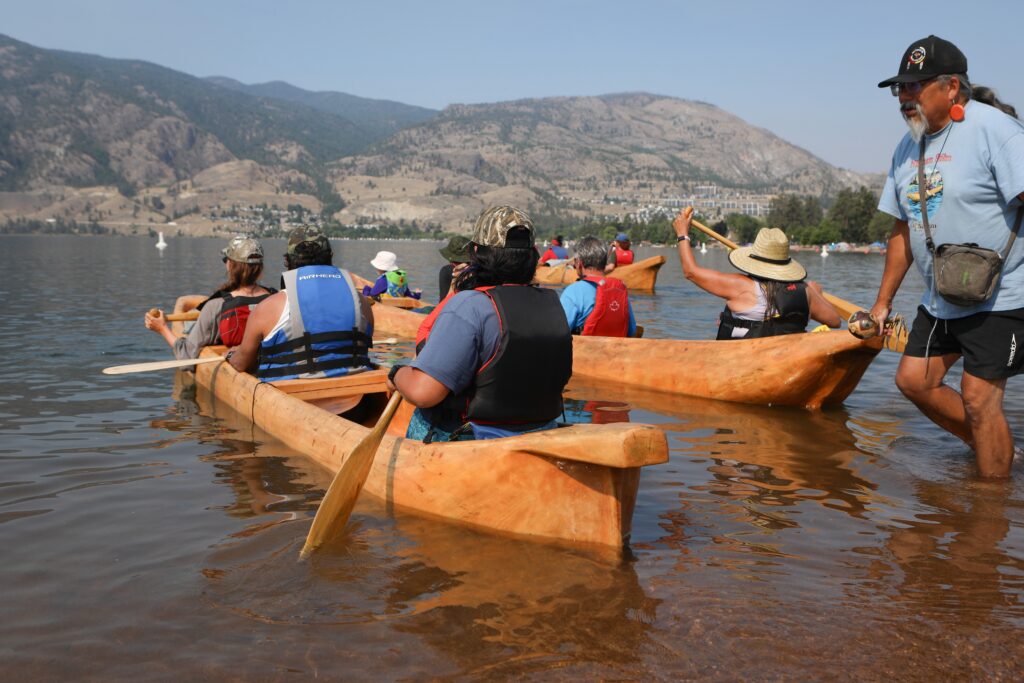Bruce Manuel, right, helps dugout canoes embark from Skaha Lake on July 31. The canoes were carved by Herman Edward, who participated in the original journey in 2001. Photo by Aaron Hemens