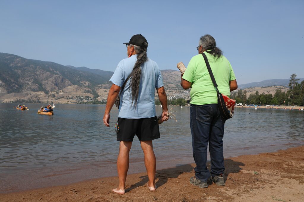 syilx Nation members Bruce Manuel and Herman Edward sing a song to send off the three canoes with syilx Nation’s 2026 Unity Trek Commemorative Paddle on July 31. The canoes were carved by Edward, who participated in the original journey in 2001. Photo by Aaron Hemens