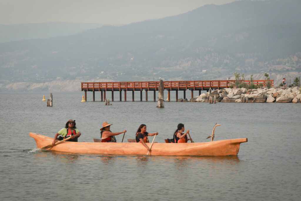 The lead canoe with the syilx Nation’s 2026 Unity Trek Commemorative Paddle nears the shores of Penticton on July 30 after arriving in Penticton, following six-days of paddling on Okanagan Lake. The canoe was carved by Herman Edward, who participated in the original journey in 2001. Photo by Aaron Hemens