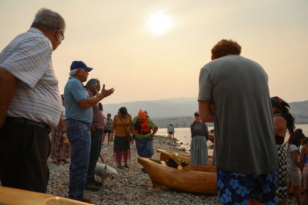 Penticton Indian Band Chief Greg Gabriel, left, speaks with paddlers with the syilx Nation’s 2026 Unity Trek Commemorative Paddle on July 30, shortly after arriving in Penticton. The canoes were carved by Herman Edward, who participated in the original journey in 2001. Photo by Aaron Hemens